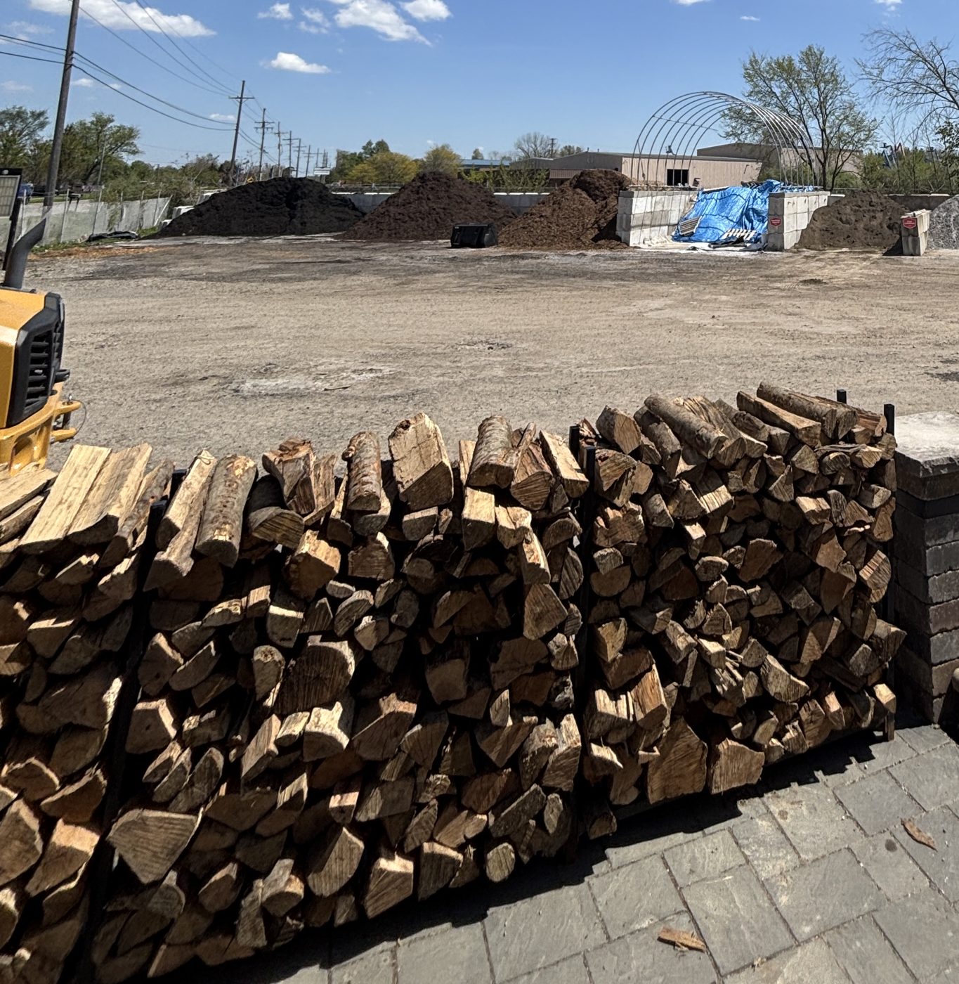 Stacked firewood with axe and FIREWOOD sign at Miller's
